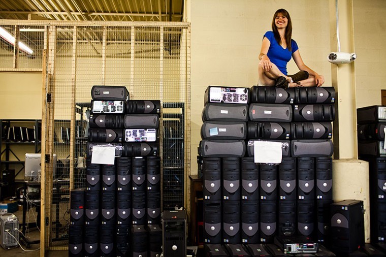 Recycling and Surplus Coordinator Sara Ferguson sits on top of a
tower of surplus desktop computers at WKU Shipping & Receiving
that are among dozens of old school supplies that will be sold,
fixed up or donated.
