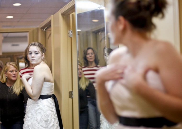 In preparation for her wedding in January, 22-year-old Allie
Duggin, from Glasgow, Ky., tries on wedding dresses Thursday at
Michelle’s Consignment with the help of her mother, Carol Duggin,
and sales manager Kirby Troyan. With Duggin deciding between a
short white dress and a short blue dress, her mother said, “She is
very untraditional, as you can see from her dress choice.”
