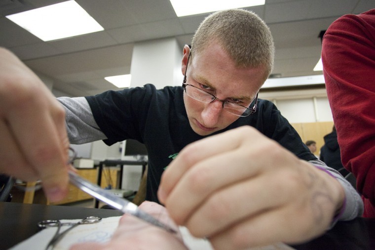 Austin Adams, a high school student from Somerset who has an
interest in plastic surgery, practices suturing a pig’s foot with
students in Alpha Epsilon Delta’s pre-medical society. COOPER
BURTON/Herald
