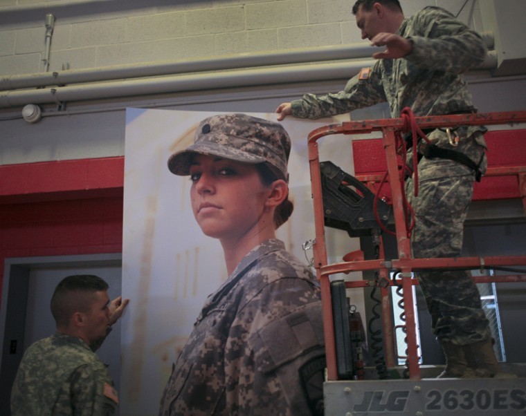 Sgt. 1st Class Richard A. Villeneuve (left) and Sgt. 1st Class
Charles K. Honaker hang a banner in E.A. Diddle Arena Friday as a
part of a $38,000 ROTC branding project at WKU. The project is cost
free to the university and to ROTC.

