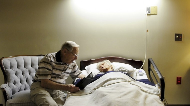 Robert Mounce reads to his wife, Jean, in her room at Village
Manor, a nursing home in Bowling Green.
