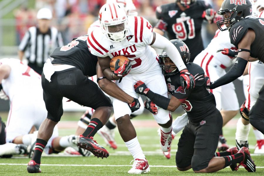 Western Kentucky running back Antonio Andrews (center), is brought down by Arkansas State defensive back Chaz Scales (right) and Don Jones during the game Saturday, Sept. 29, 2012 at Liberty Bank Stadium in Jonesboro, Arkansas. This is the second season in a row that Western Kentucky has begun Sun Belt Conference play agains the Arkansas State Red Wolves. In the last matchup, The Hilltoppers lost 22-26.
