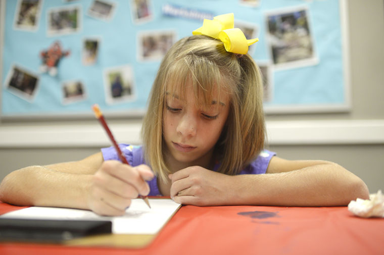 Sarah Ssler, 10, of Bowling Green draws in her Side by Side art class. The Side by Side classes are intended to get children with developmental and behavioral disorders expressing themselves through art.