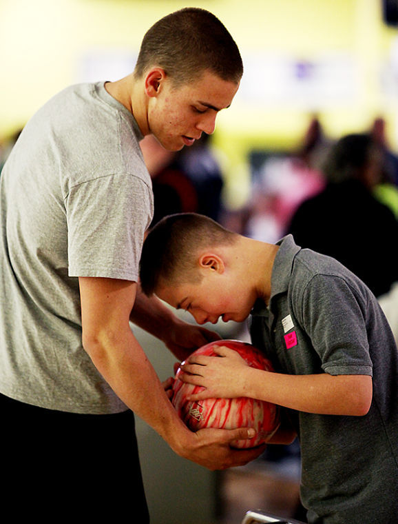 Louisville Freshman Michael Bryar hands a participant a bowling ball before stepping up to the lane. Bryar volunteered with fellow members of WKUs Inclusive Ministries program Saturday at the Area 5 Special Olympics Bowling Tournament.