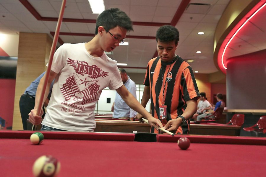 Brazilian senior Yoshiaki Tsuchida places the stick of second year ESLI student Felix Nascimento of Donesk, Ukraine, and Luanda, Angola, during a game of pool Sunday night in the DSU rec room. The two, who met because they share a common language of Portuguese, said they dont mind paying the fees to play. I think its cheap, Tsuchida said, explaining that he usually pays more to play pool in Brazil. Nascimento agreed that the price is not so much. Leanora Benkato/HERALD