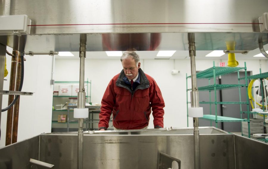 Jack Rudolph, a professor of agricultural education at WKU, removes a cover to the cheese vat at the Taylor Center on WKU's farm in Bowling Green, Kentucky, on Monday, Feb. 22, 2016. Rudolph's 