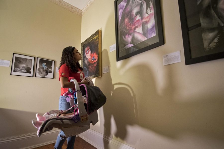 Victoria Mitchell, 20, of Bowling Green looks at artwork on display with her six-month-old daughter, Isabella Keaton on Friday, October 14, at the FFOYA House. I came to this event tonight because I was in a domestic violence relationship with her father and its so nice to go to hear other peoples stories, Mitchell said. Ebony Cox/HERALD