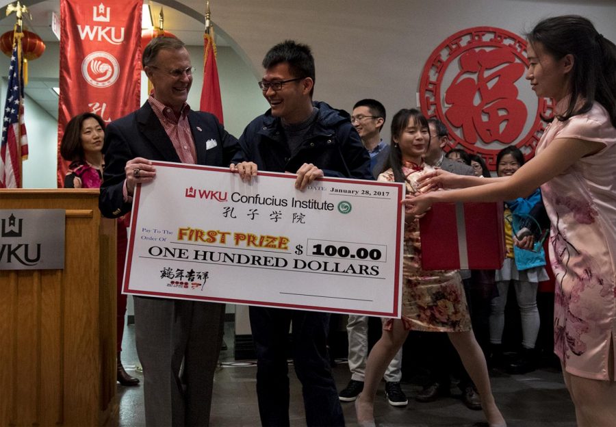 Gary Ransdell offers a one-hundred-dollar check to student Lin Weipeng, during the chinese new year celebration on Sat. Jan. 27, 2017 at the Confucius institute.