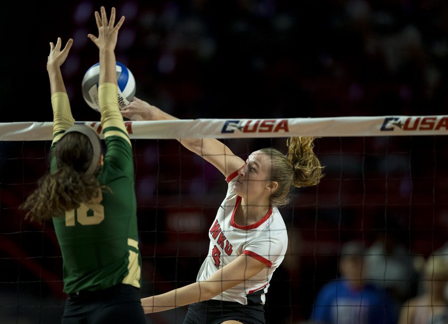 WKU junior Rachel Anderson (4) spikes the ball into the arms of Charlotte sophomore Jocelyn Stoner (18) in the first game of the C-USA Championship Tournament. WKU went on to sweep the tournament, winning it for the fourth year in a row.