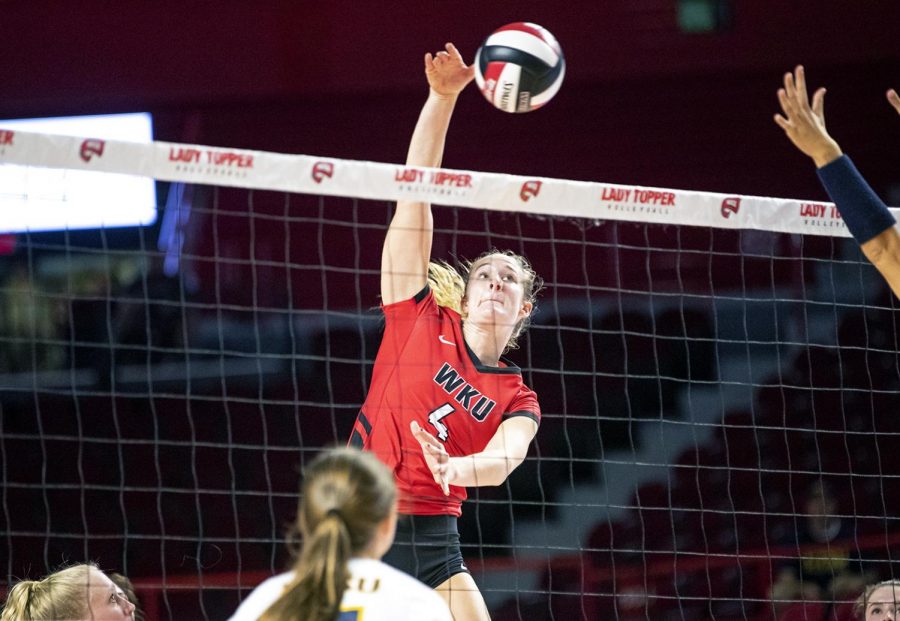 Senior middle hitter Rachel Anderson (4) spikes the ball over the net past ETSU for one of her 10 kills at Diddle Arena Sept. 14. Anderson had 10 kills and four blocks for the Lady Toppers in a 3-0 win against the Bucs.