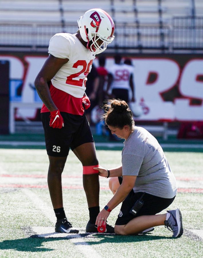 Jessica Judd wraps Dionté Ruffin’s knee after warm ups at practice on Wednesday afternoon, Sep. 18, 2019, in Houchens-Smith Stadium.