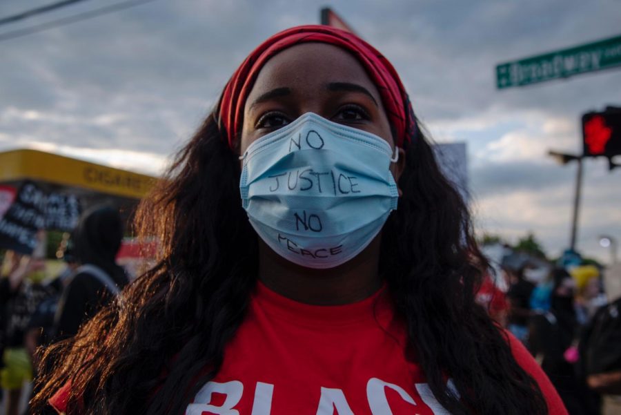 A protester wears a face mask reading “no justice, no peace,” at the intersection of 26th St and Broadway in Louisville on June 1. Protesters marched from Jefferson Square to Dino’s Food Mart on S 26th St and W Broadway in honor of David McAtee’s recent death at the hands of the National Guard and LMPD.