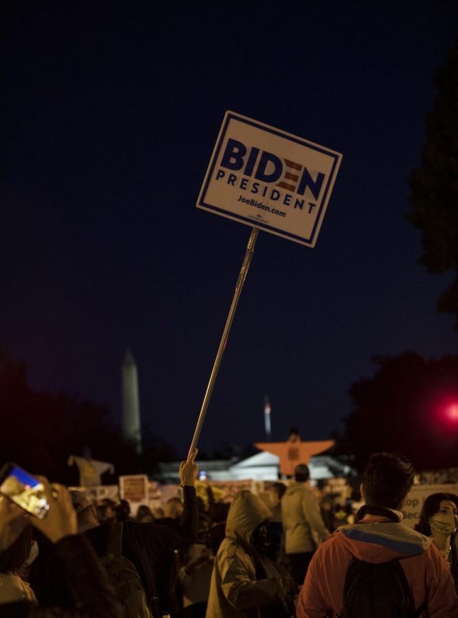 A person holds Biden presidential campaign signage outside of the White House on the night of election day, November 3, 2020.
