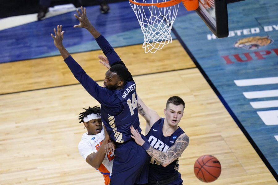 Florida’s Tyree Appleby (left) passes around Oral Roberts’ DeShang Weaver (middle) and Carlos Jurgens during the first half of the Golden Eagles’ win in the second round of the NCAA Tournament on Sunday at Indiana Farmers Coliseum in Indianapolis.