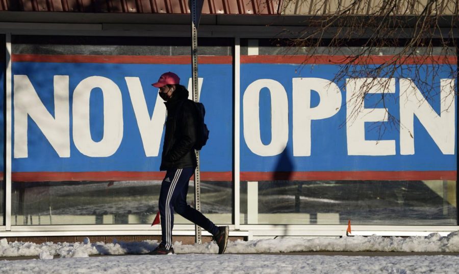 A pedestrian in a face covering walks past the sign plastered on the windows of a restaurant to announce that it is open after closure because of the coronavirus Thursday, Feb. 25, 2021, in Boulder, Colo.