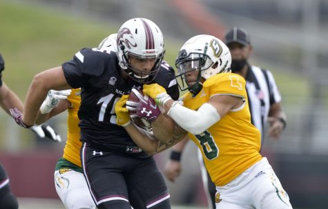 SIU running back Javon Williams Jr. (15) powers through the tackle by Southeastern Louisiana defensive back Donniel Ward-Magee (8) during the fourth quarter at Saluki Stadium on Saturday in Carbondale. The Salukis went on to win 55-48.