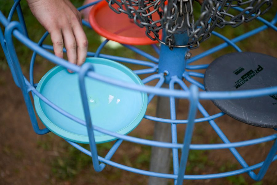 A member of the WKU Disc Golf Club collects his disk from the basket.