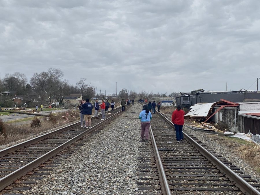 A crowd paces the rails adjacent to Creason Street, assessing the major damage to a row of homes.