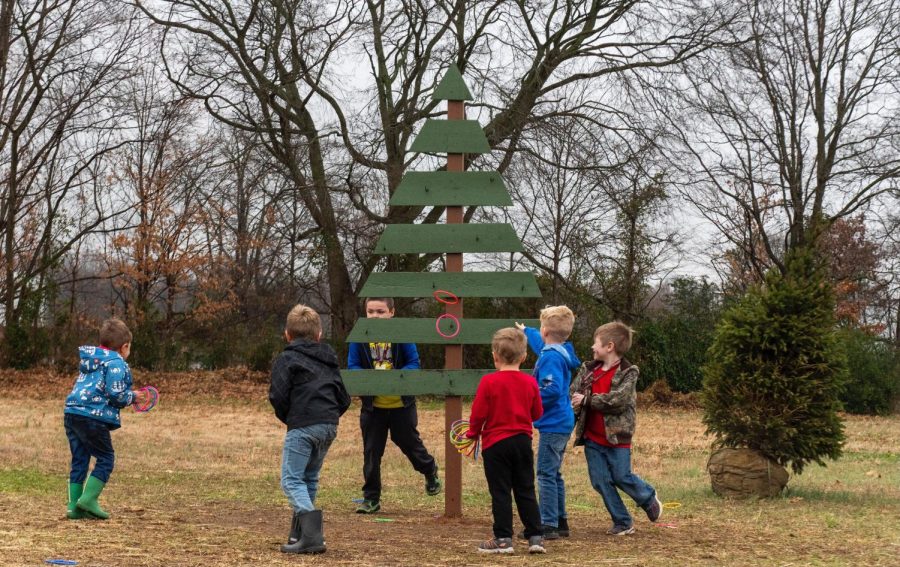A group of young boys play ring toss on a Christmas tree while visiting the Reindeer Farm. Other games at the farm include corn hole, giant Connect Four and giant chess.