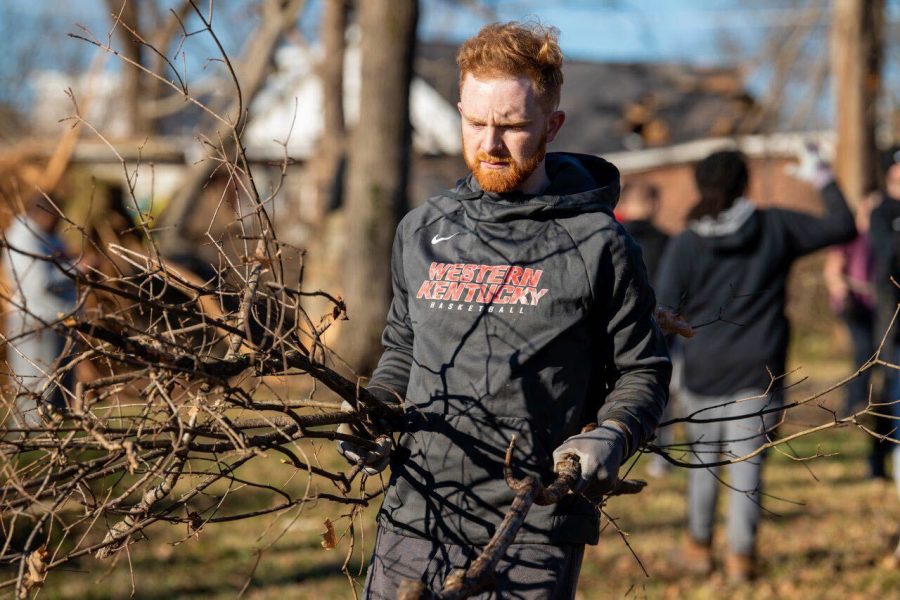 Jacob Hayslip, a graduate assistant with WKU’s men’s basketball team, carries debris in a neighborhood off of Normal Street in Bowling Green on Monday, Dec. 13. The team came to clean up just two days after their 71-48 victory over Ole Miss.