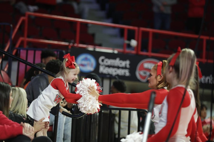 WKU cheerleaders interact with a young fan on the sidelines.