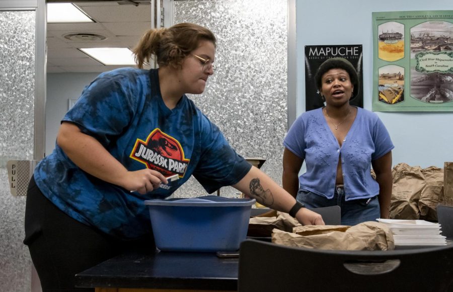 Ali Shackelford, a senior biology major with a concentration in anthropology, right, talks to Heather Pursley while she cleans glass. Shackelford has experience washing bones for class but comes to the wash nights to clean the artifacts for fun. Allie Schallert / College Heights Herald