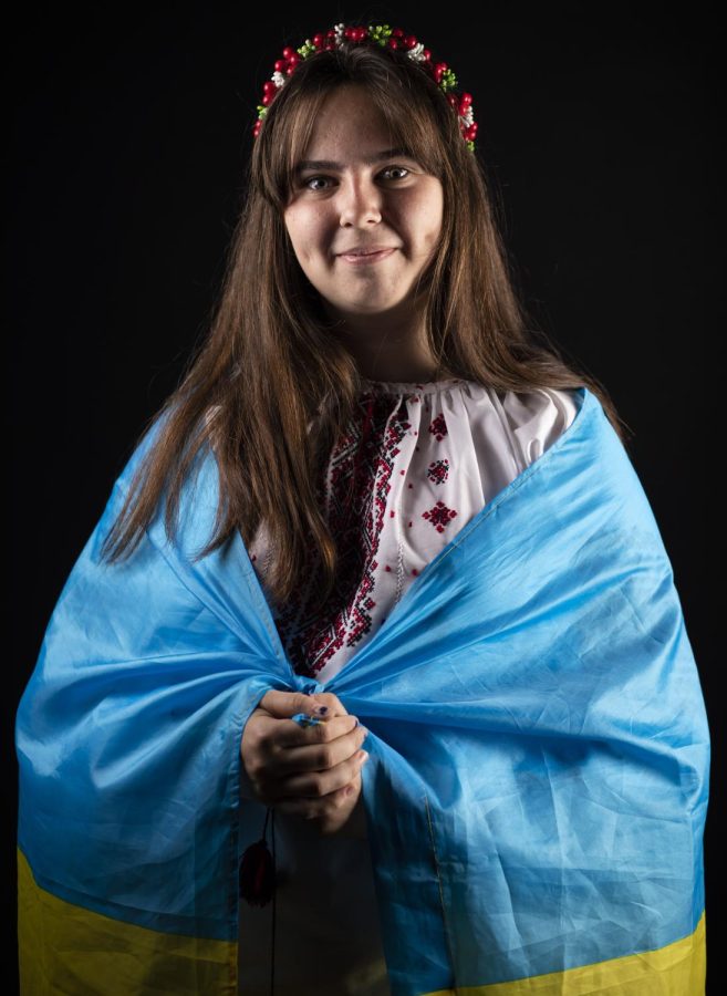 WKU student Mariia Novoselia poses for a portrait in Jody Richards Hall draped in her Ukrainian flag and dressed in traditional Ukrainian attire.