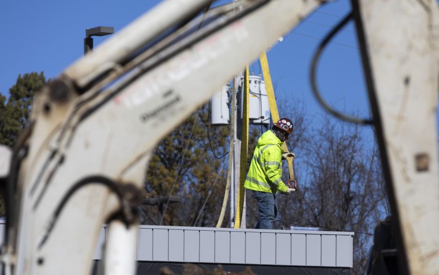 A construction worker helps lower the newly built 7 Brew drive-thru coffee shop into position located on Scottsville road on Friday, Feb. 3, 2022.