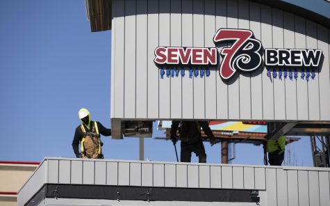 Construction workers help lower the newly built 7 Brew drive-thru coffee shop into position located on Scottsville road on Friday, Feb. 3, 2022.