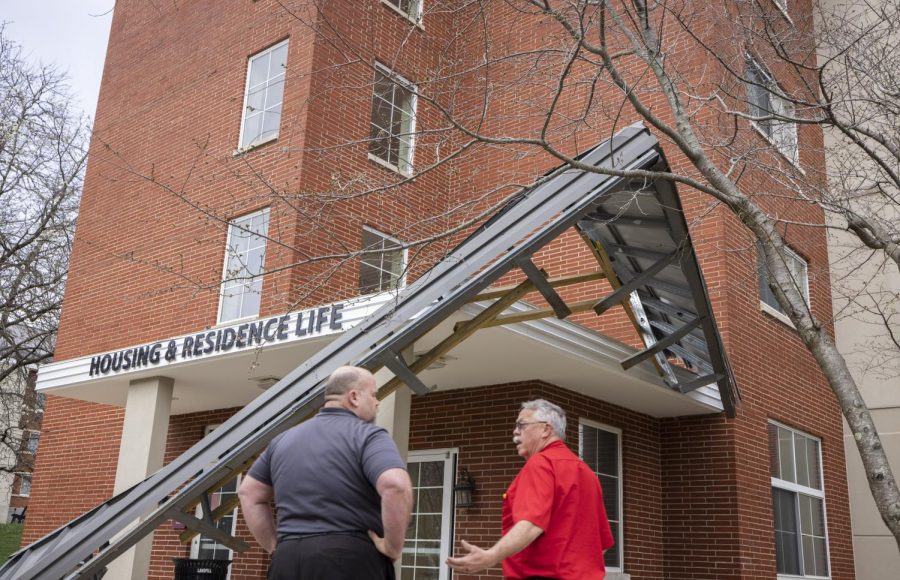 Two members of WKU Facilities Management discuss a sheet metal awning that detached from the Housing and Residence Life office, part of Southwest Hall during heavy winds on Friday, March 3, 2023.