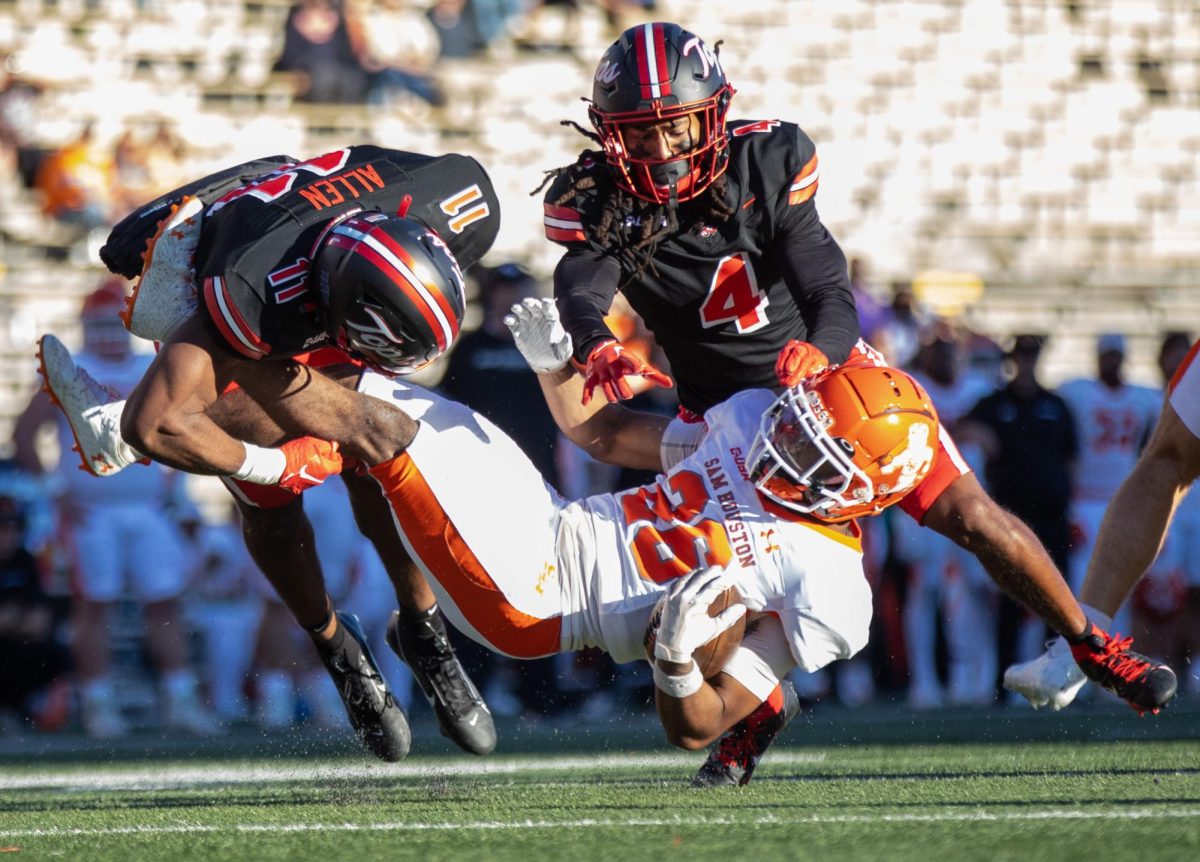 Defensive backs Talique Allen (11), left, and Anthony Johnson, Jr. (4) tackle running back Adrian Murdaugh during a game against Sam Houston State University at L.T Smith Stadium in Bowling Green on Saturday, Nov. 18, 2023.