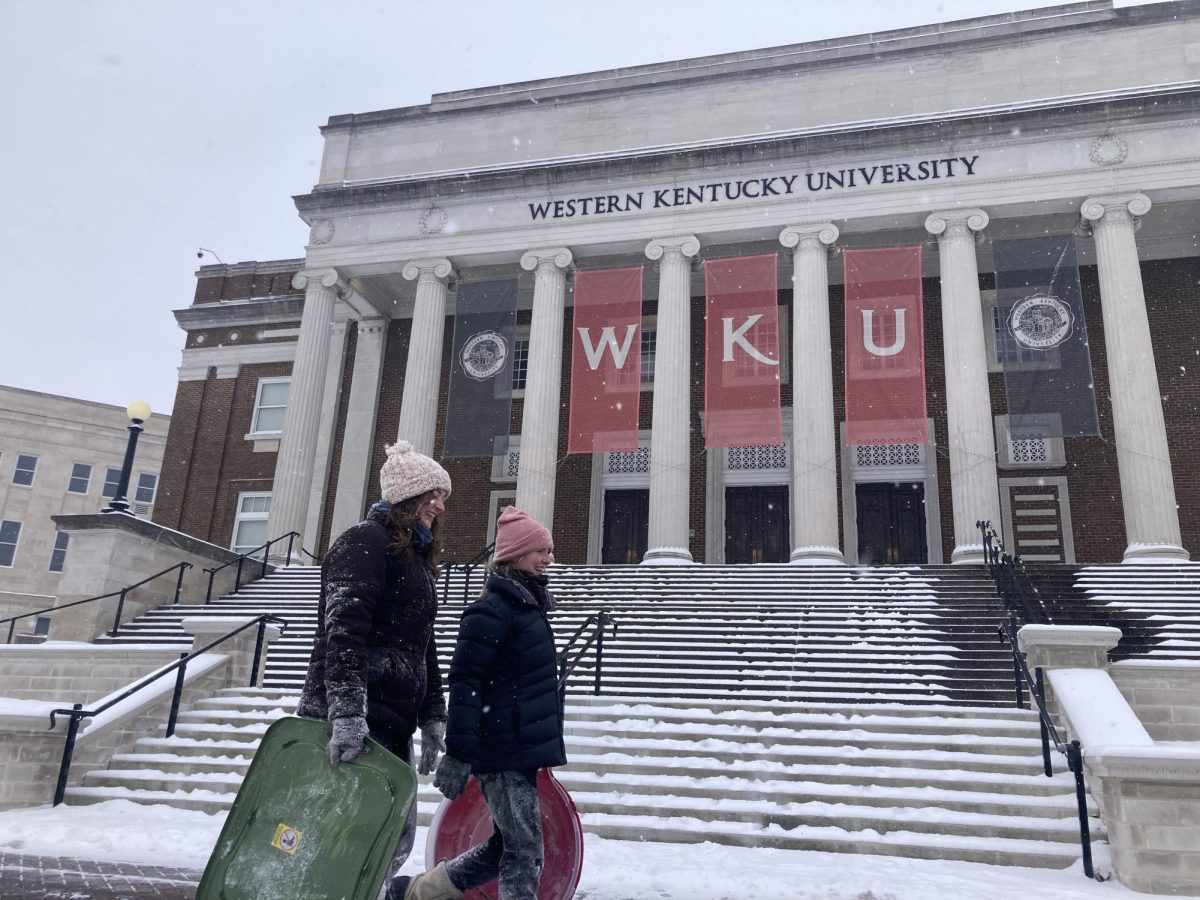 Olyvia Cool and Emma Durham walk past Van Meter Hall after sledding on WKUs campus on Jan. 15, 2024.