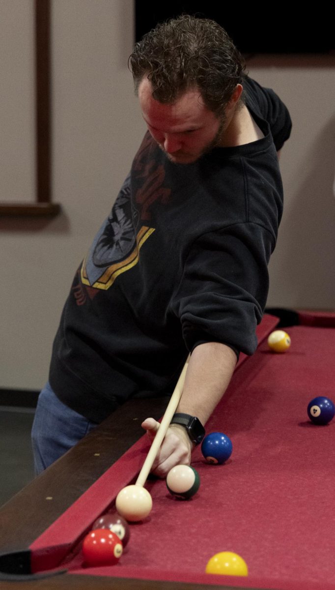 Dylan Berry, a junior math major, gets creative with his shot selection during the WKU Pool Club’s first meeting of the spring 2024 semester, on Monday, Jan. 22, 2024, in the recreation area in Downing Student Union.