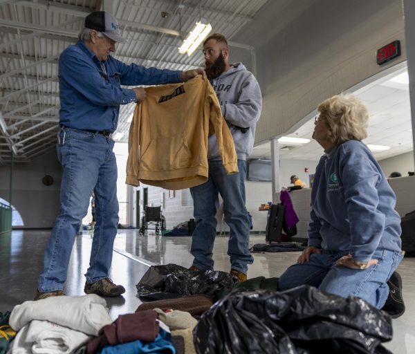 Volunteer Tim Harrington, left, holds up a hoodie for Denis Hajric, middle to examine. Harrington and volunteer Brenda Willoughby sifted through donated clothes at Kummer Recreation Center on Jan. 19. Harrington and Willoughby were volunteers from Christ Episcopal Church, which held homeless individual overnight on Jan. 16. Clothes and other items were often donated by community members the warming centers in an effort to help support the people in need.