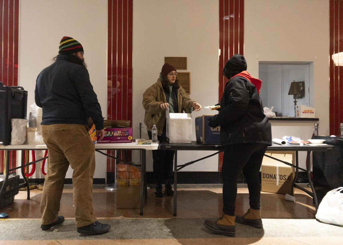 BG Neighbors worker Emily Witthuhn and volunteers Johnalma Barnett and Patrick Weeks clean up after closing the warming center station at the Capitol Theatre after the homeless individuals departed to Christ Episcopal Church on Jan. 16.