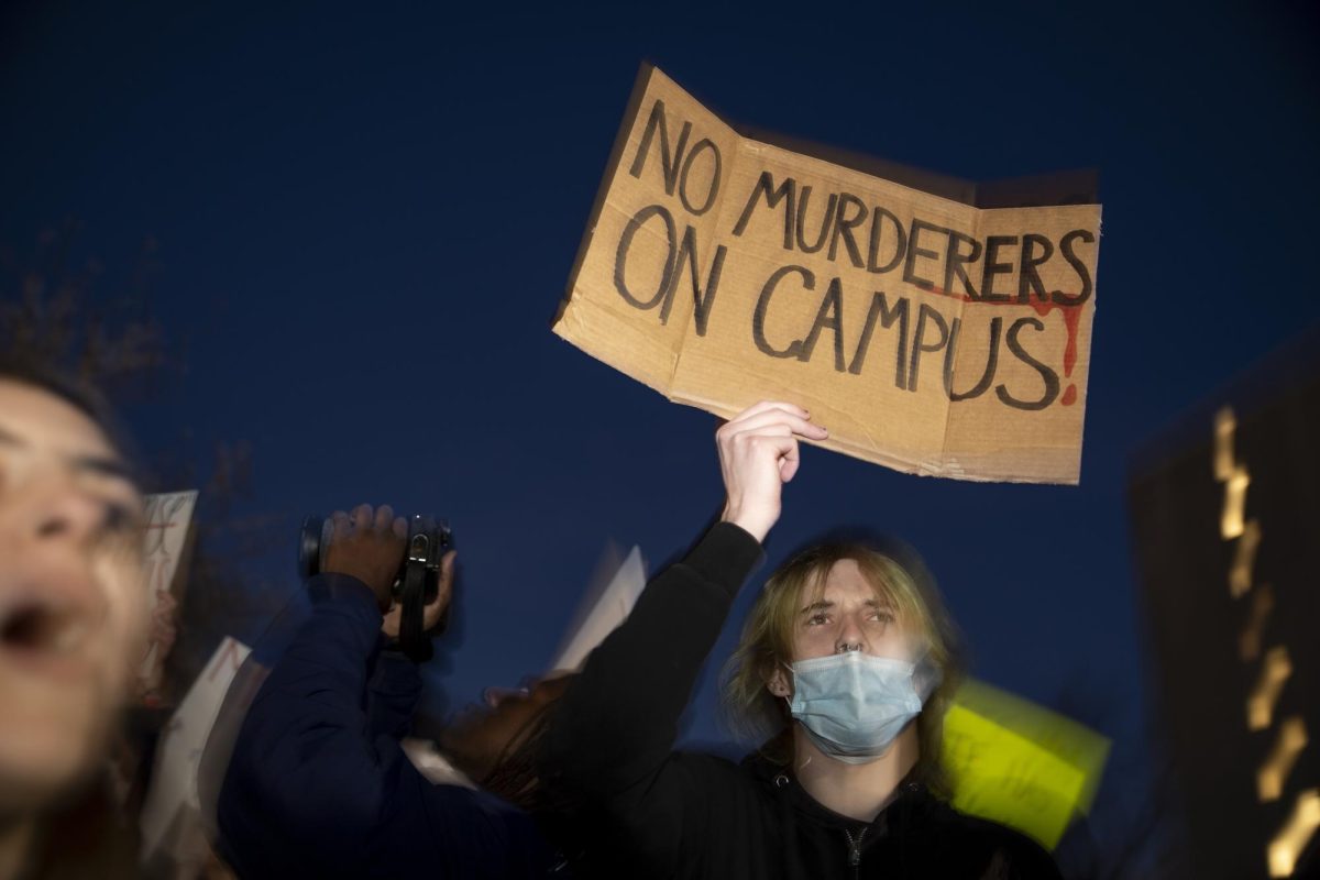 Noah Ballard, a political science major, holds his sign outside of Downing Student Union on Wednesday, March 27, 2024. I dont think killers belong on campus, Ballard said.
