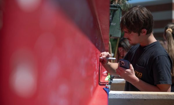 Zander Brock, a sophomore accounting major, signs his name on a metal beam before it is lifted and placed in the new Gordon Ford College of Business building on Thursday, April 18, 2024.
