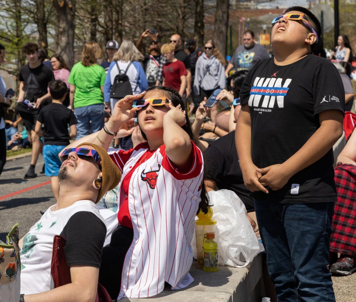 From left: Jose Hernandez, Amberlynn Cortez, 13, and Adrian Cortez, 12, of Milwaukee check the status of an eclipse while waiting for totality to begin in downtown Evansville, Ind. on Monday, April 8, 2024. 