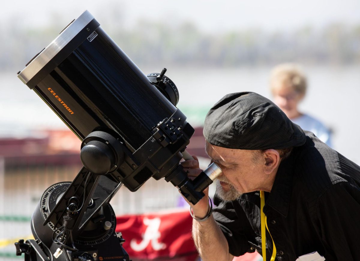 Randy Chapman of the Evansville Astronomical Society looks through a telescope before a viewing of the total solar eclipse in downtown Evansville, Ind. on Monday, April 8, 2024. Chapman explained that he’s been interested in astronomy for around 50 years and that his goal is to educate the public. 