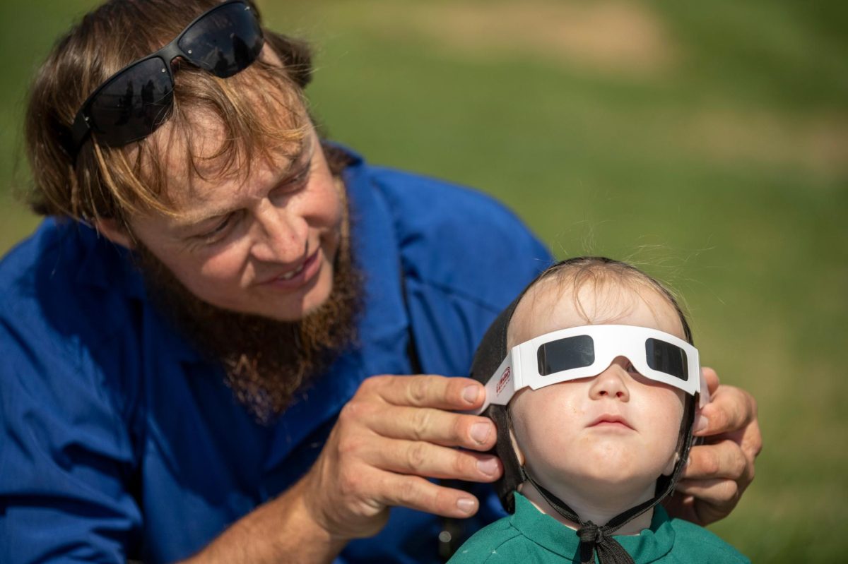 Jacob Borntreger holds glasses for his daughter during a total solar eclipse in Evansville, Ind. on Monday, April 8, 2024. 