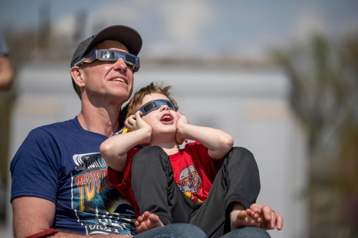 Ben sits with his father Bryan Barnes during a total solar eclipse in Evansville, Ind. on Monday, April 8, 2024. 