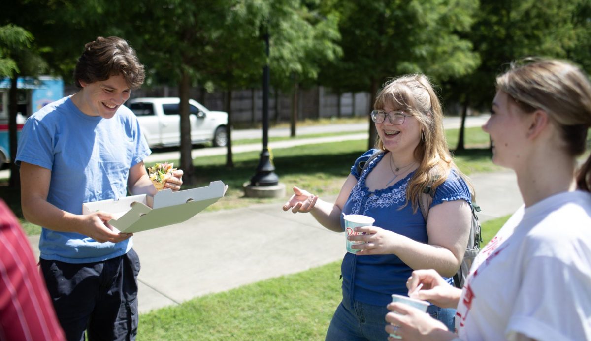 From left: Freshman honors students Daniel Thelen, Atiana Spivey and Jordan Wonka chat about spending their first week on campus at the WKU Honors College Back Bash at the Mahurin Honors College back lawn on Wednesday, Aug. 21, 2024. 