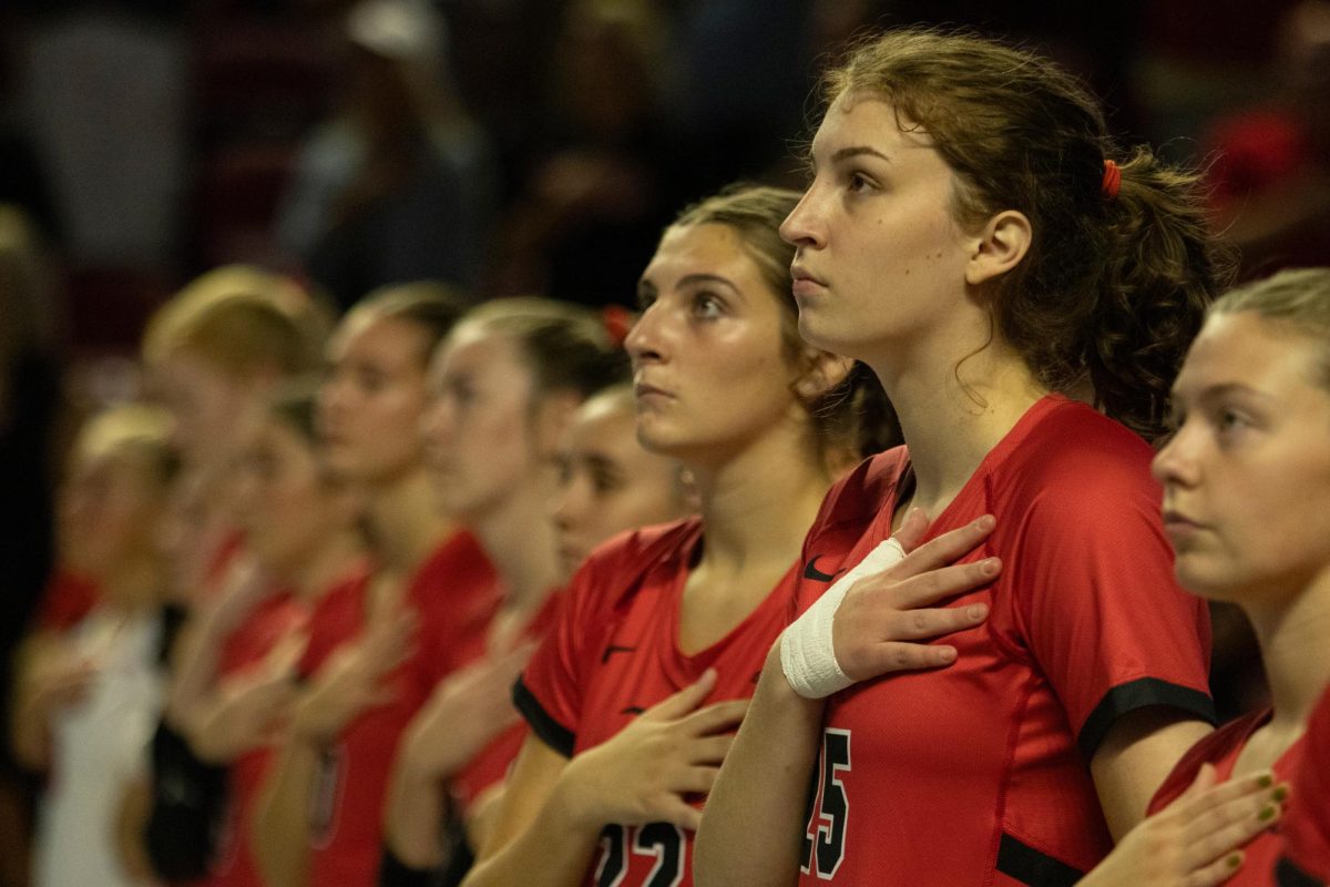 Middle hitter, Izzy Van De Wiele (25), right, and outside hitter Faith Young (22) stand with their team for the national anthem before they go up against Arkansas State University at Diddle Arena on Friday, Sept. 20, 2024. 