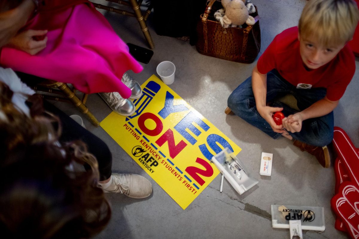 Samuel Towe (right) finds time to play next to his mother Laura Towe before the Americans for Prosperity “Yes On 2” rally at the La Gala event center in downtown Bowling Green, on Monday, Oct. 28, 2024. “I’m fortunate to be able to choose [schools]. I want other families who may not have the means to be able to choose as well,” Laura Towe said.  