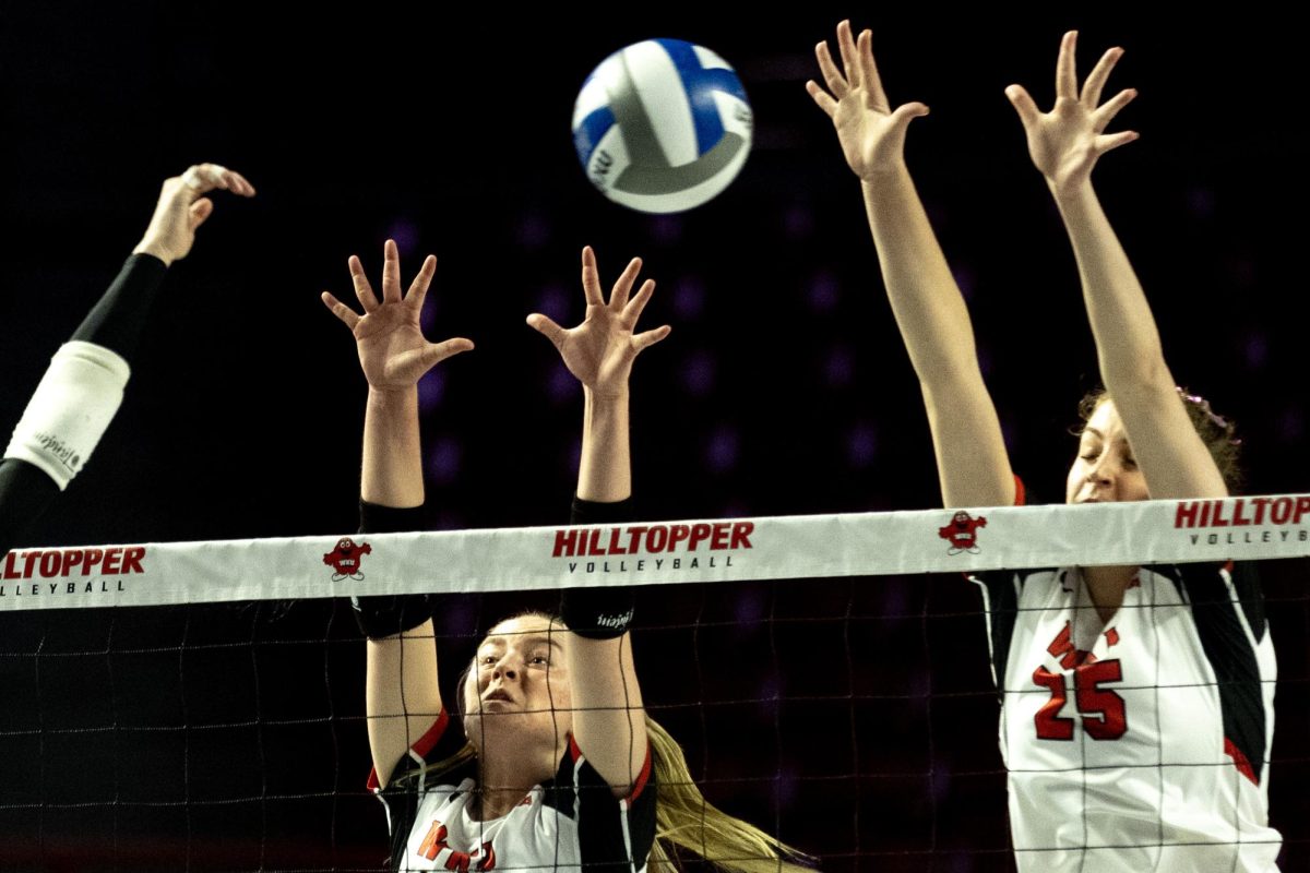 WKU setter Callie Bauer (14) and middle hitter Izzy Van De Wiele (25) attempt to block an attack from Kennesaw State’s Kieran Staley (8) during WKU’s 3-0 victory in Diddle Arena on Friday, Oct. 4, 2024.