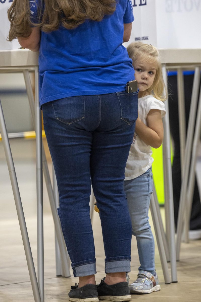 Kyleigh Simpson (3) grabs her moms leg while she votes during the last day of voting on Tuesday, Nov. 5, 2024 at Warren Central High School.