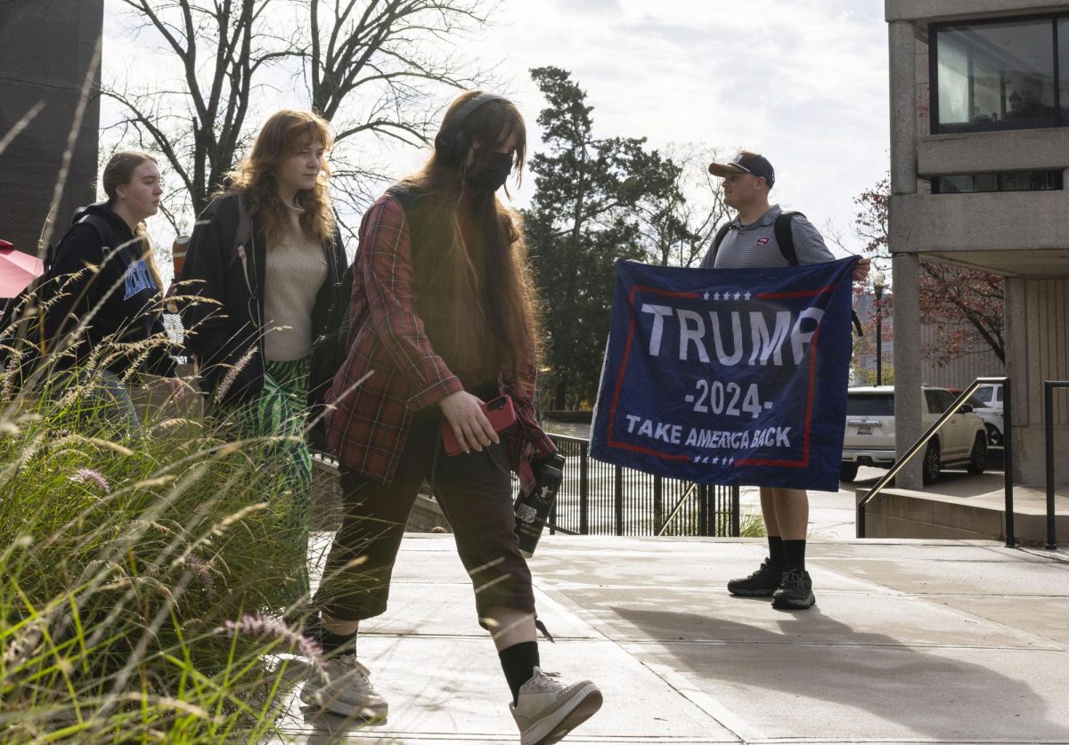 Students walk past WKU senior Jacob Combs as he holds a flag in support of president-elect Donald Trump outside of the Commons at Helm Library on Wednesday, Nov. 6, 2024.