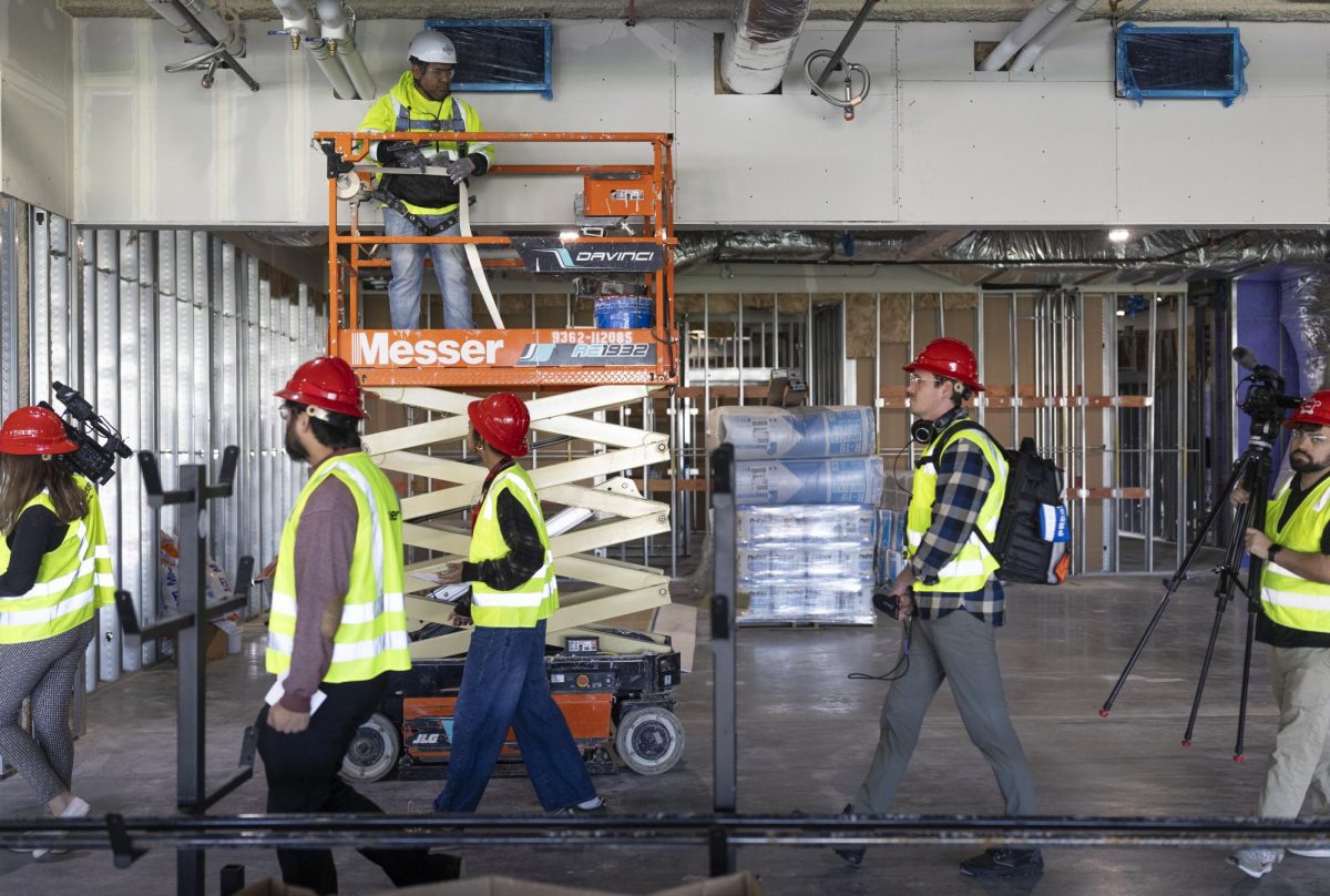 A construction worker pauses construction on the new Gordon Ford College of Business building so members of the media can walk safely past during a walkthrough on Tuesday, Nov. 12, 2024.