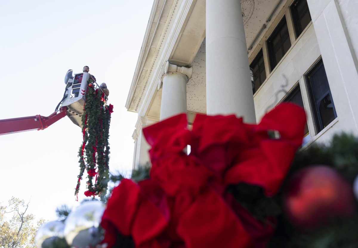 Billy Finn and Chris Bartley prepare to hang holiday wreaths on Cherry Hall on Tuesday, Nov. 12, 2024. 