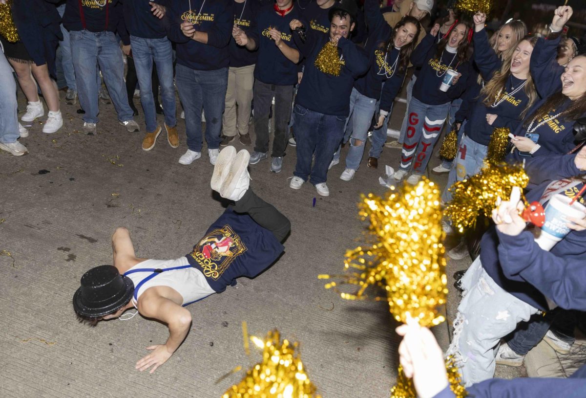 Ari Obando performs ‘the worm’ dance as his fraternity waits for the parade’s start on Friday, Nov. 15, 2024.